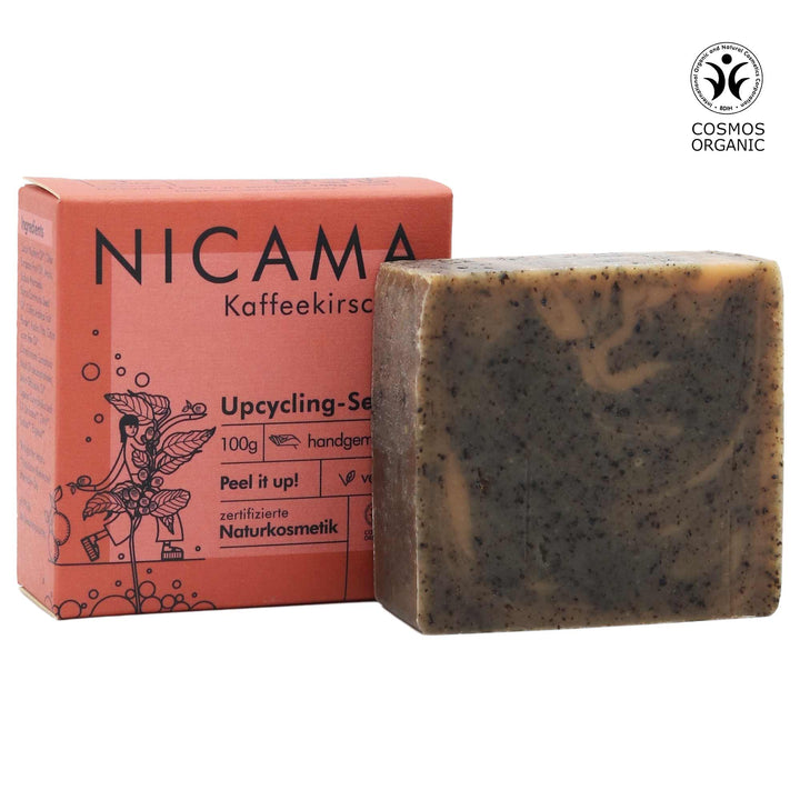 Seifenstück neben Verpackung mit Aufschrift "NICAMA Kaffeekirsch Upcycling-Seife", zertifizierte Naturkosmetik.