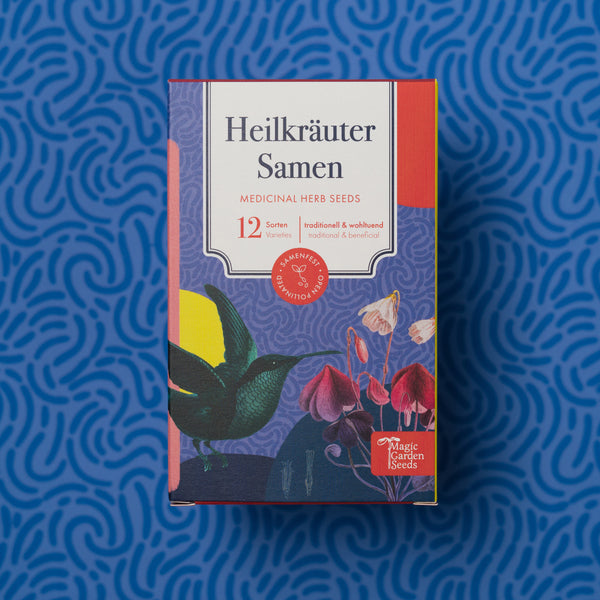Packung mit Heilkräutersamen mit dem Titel "Heilkräuter Samen", umgeben von illustrierten Pflanzen und einem Vogel, vor einem blauen Musterhintergrund.