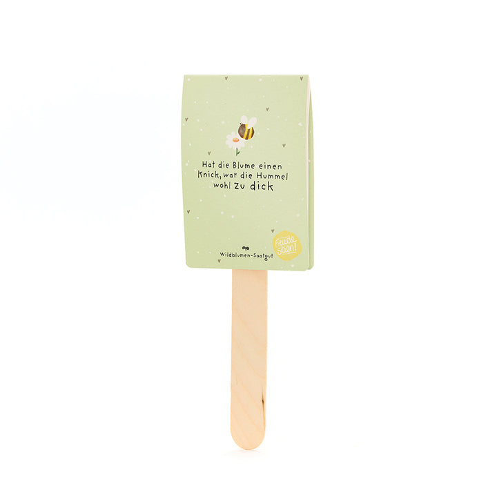 Grüner Papieranhänger mit einem Bienenmotiv und dem Spruch „Hat die Blume einen Knick, war die Hummel wohl zu dick“ auf einem Holzstab.