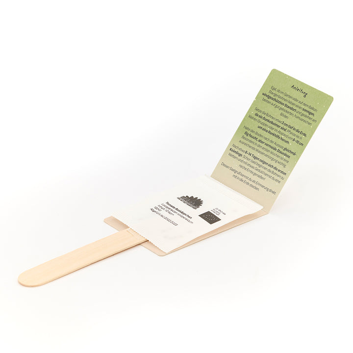 Holzstab mit einem Umschlag, der eine grüne Anleitungskarte und ein Samentütchen enthält.