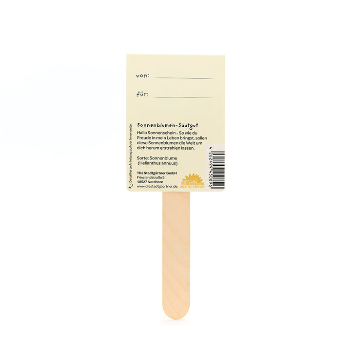 Ein Holzstäbchen mit einem daran befestigten Etikett, das Sonnenblumen-Saatgut beschreibt und Felder für „von“ und „für“ zum Ausfüllen enthält.