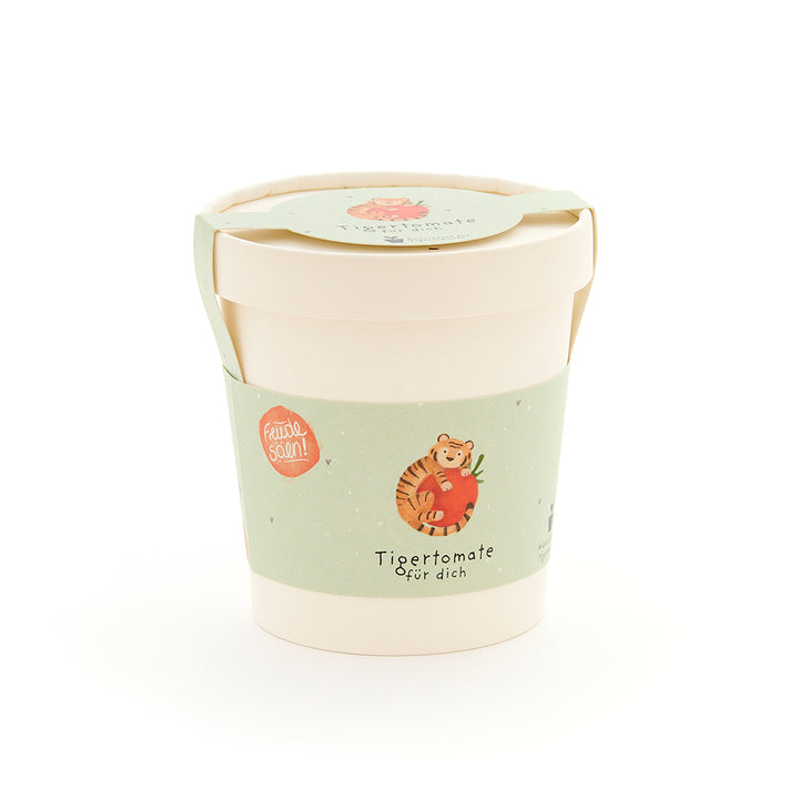Becher mit grünem Etikett, auf dem ein Tiger mit einer Tomate und der Text "Tigertomate für dich" abgebildet ist.
