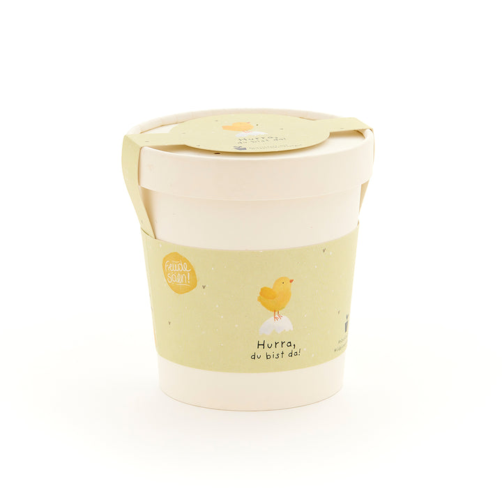 Becher mit gelbem Etikett, darauf ein Küken und die Aufschrift "Hurra, du bist da!"