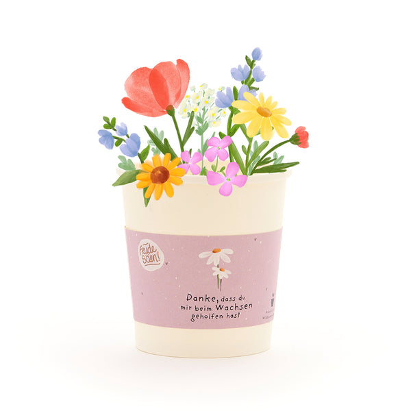 Ein Blumentopf mit bunten, gezeichneten Blumen und einer Banderole, auf der steht: "Danke, dass du mir beim Wachsen geholfen hast."